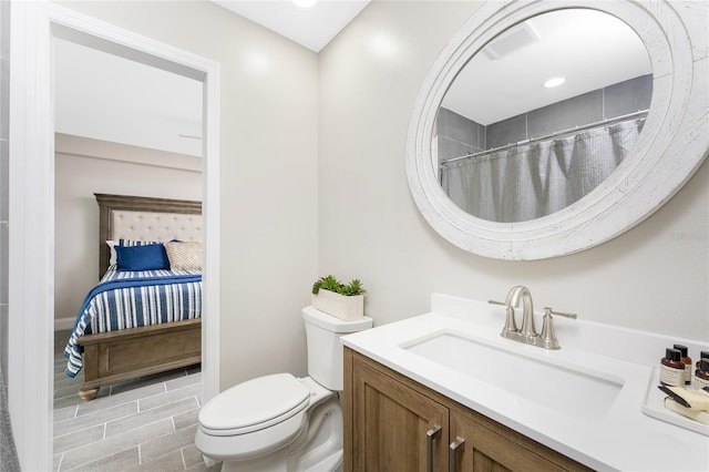 ensuite bathroom featuring toilet, ensuite bath, and vanity