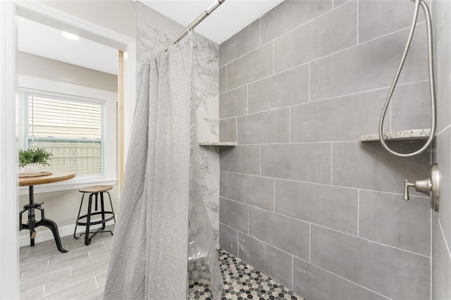 full bathroom featuring baseboards, a tile shower, and wood finished floors