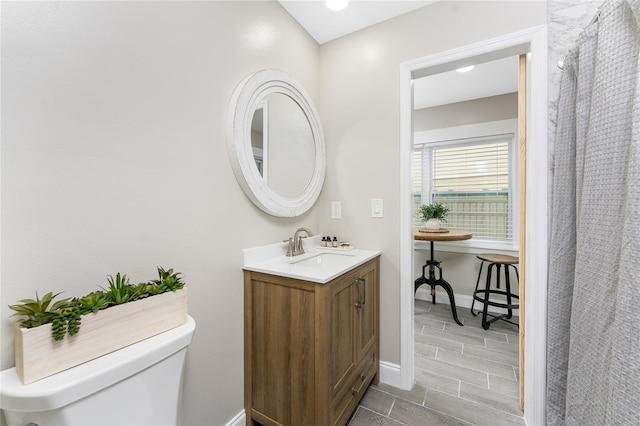 full bathroom featuring baseboards, vanity, and toilet