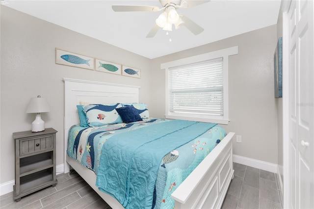 bedroom with a ceiling fan, wood finish floors, and baseboards