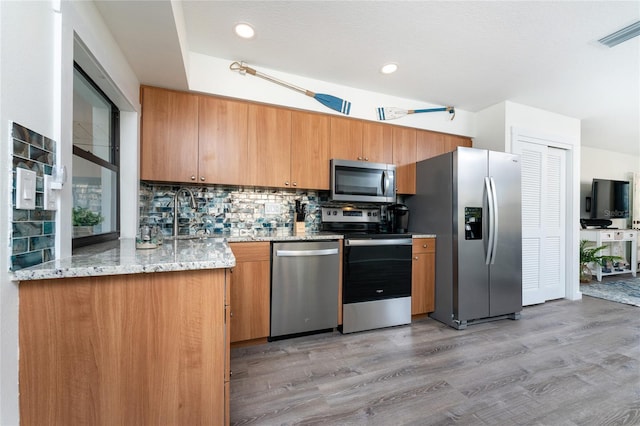 kitchen with light wood finished floors, stainless steel appliances, visible vents, decorative backsplash, and a sink