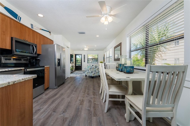 kitchen featuring brown cabinets, stainless steel appliances, visible vents, ceiling fan, and wood finished floors