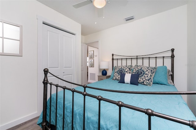 bedroom with baseboards, visible vents, a ceiling fan, wood finished floors, and a closet