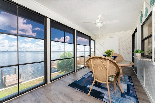 sunroom / solarium with ceiling fan and a water view