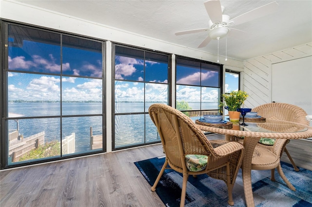 sunroom featuring ceiling fan and a water view