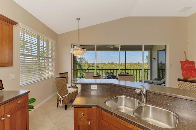 kitchen with lofted ceiling, hanging light fixtures, a sink, and brown cabinets