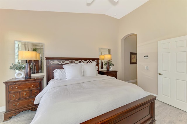 bedroom with baseboards, arched walkways, a ceiling fan, lofted ceiling, and light wood-style floors