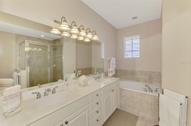 bathroom with double vanity, a garden tub, a shower stall, and a sink