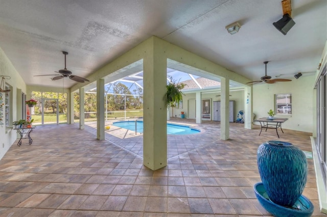 pool with glass enclosure, ceiling fan, and a patio area