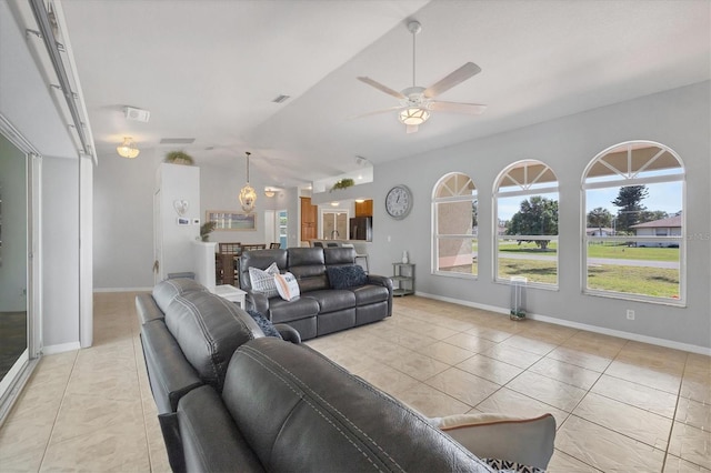 living area featuring lofted ceiling, ceiling fan, light tile patterned flooring, and baseboards