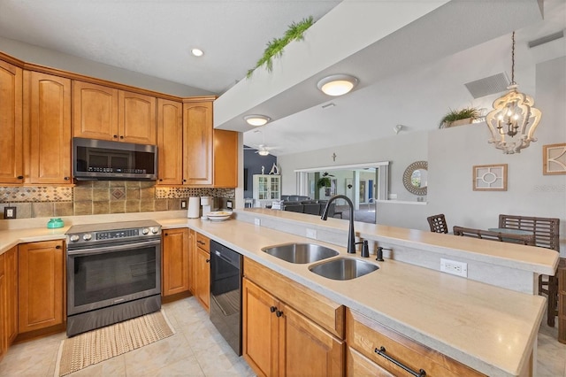 kitchen featuring appliances with stainless steel finishes, light countertops, a sink, and a peninsula