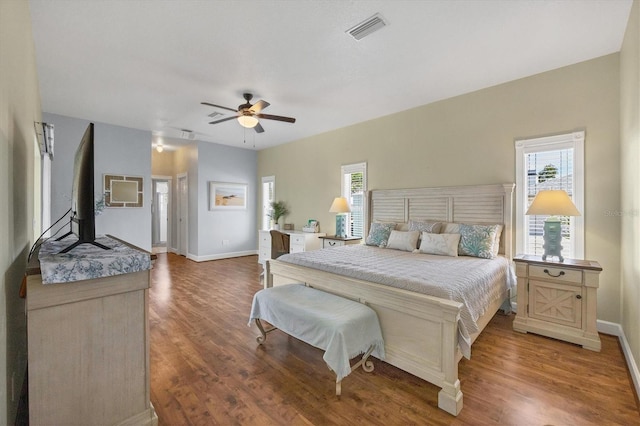 bedroom featuring wood finished floors, visible vents, baseboards, and multiple windows