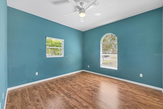 empty room with ceiling fan, baseboards, and wood finished floors