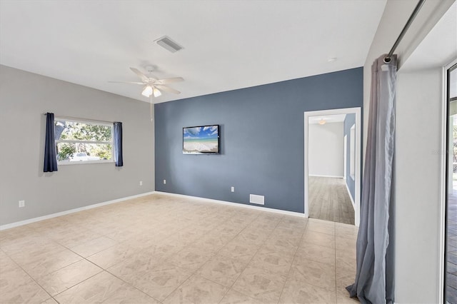 empty room with baseboards, visible vents, and ceiling fan