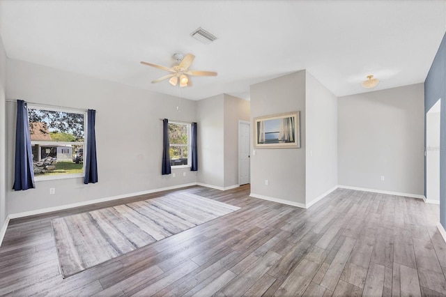 unfurnished room with a ceiling fan, wood finished floors, visible vents, and baseboards