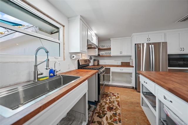 kitchen with under cabinet range hood, stainless steel appliances, a sink, wood counters, and white cabinets