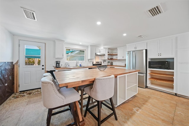 kitchen with open shelves, stainless steel appliances, butcher block counters, visible vents, and white cabinetry