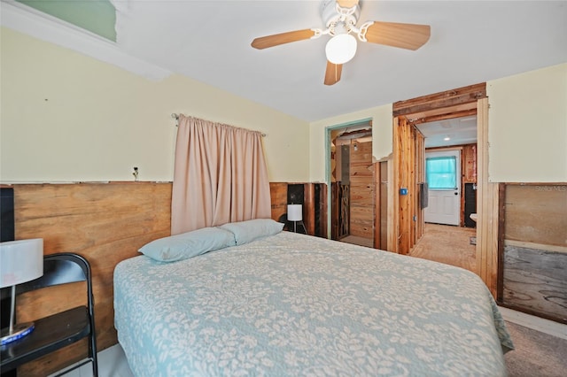 bedroom with a ceiling fan, a wainscoted wall, and light colored carpet