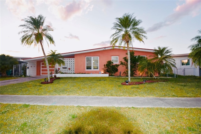 single story home featuring driveway, a garage, a front lawn, and stucco siding