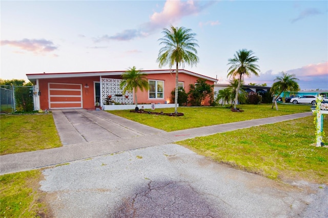 view of front of property with a front yard, concrete driveway, an attached garage, and stucco siding