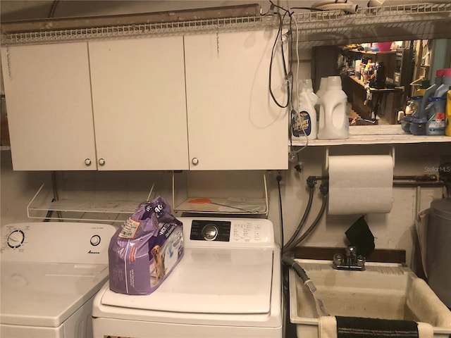 laundry area featuring cabinet space, separate washer and dryer, and a sink