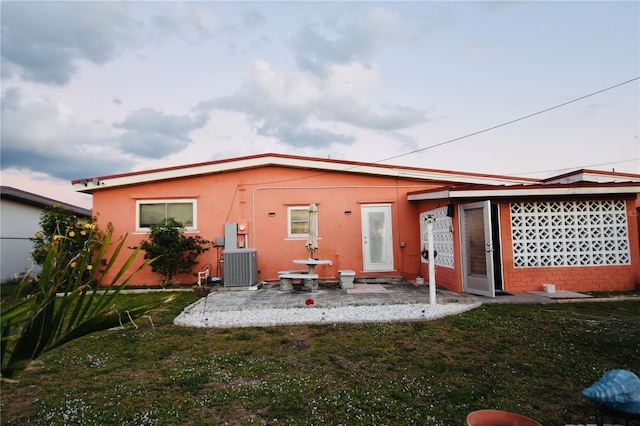 rear view of house with central AC and a lawn