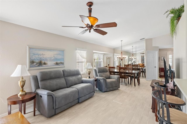 living room with ceiling fan with notable chandelier, baseboards, light wood-style floors, and vaulted ceiling