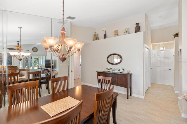 dining space with light wood-type flooring, visible vents, high vaulted ceiling, and an inviting chandelier