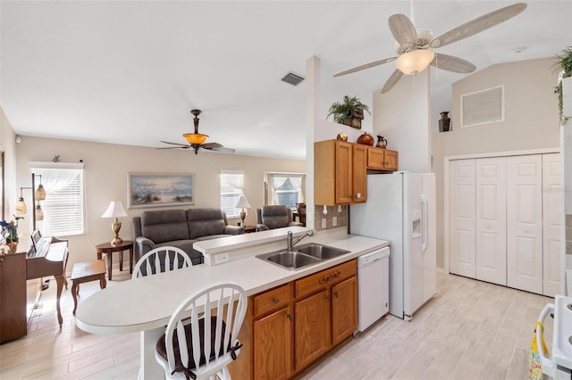 kitchen featuring white appliances, visible vents, a peninsula, a sink, and light countertops