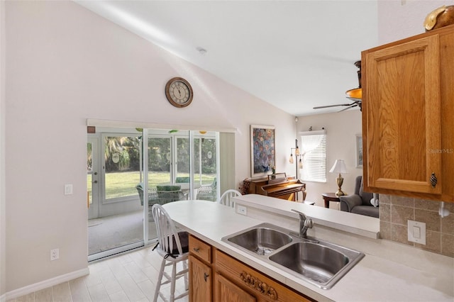 kitchen featuring a sink, lofted ceiling, brown cabinets, and light countertops