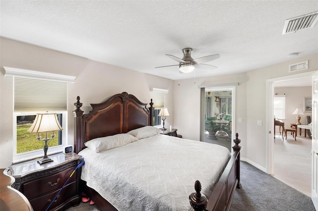 carpeted bedroom featuring a textured ceiling, baseboards, visible vents, and ceiling fan