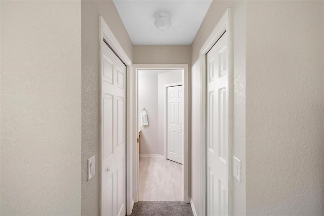 hall featuring baseboards and carpet floors