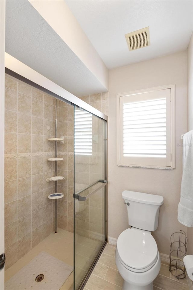 bathroom with visible vents, baseboards, toilet, and a stall shower