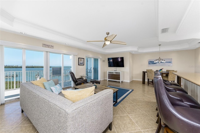 living room with baseboards, a tray ceiling, visible vents, and crown molding