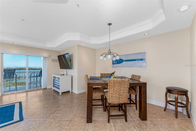 dining space with baseboards, ornamental molding, and a raised ceiling