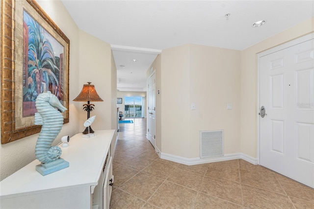 hall featuring light tile patterned floors, visible vents, and baseboards