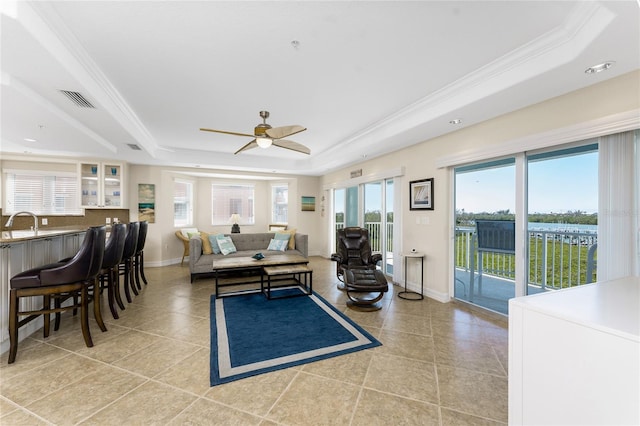 living area featuring ornamental molding, a tray ceiling, visible vents, and baseboards