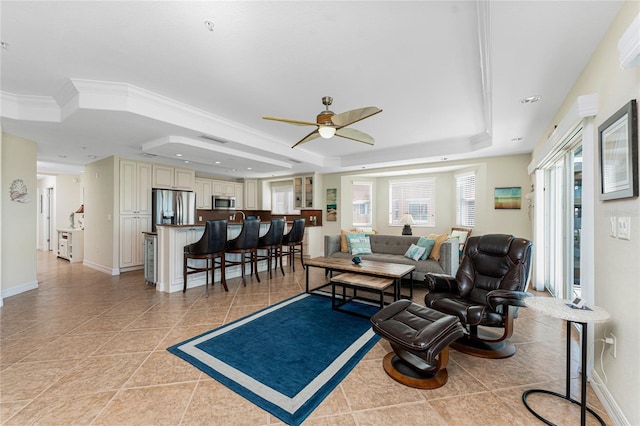 living room with light tile patterned floors, a tray ceiling, crown molding, and baseboards