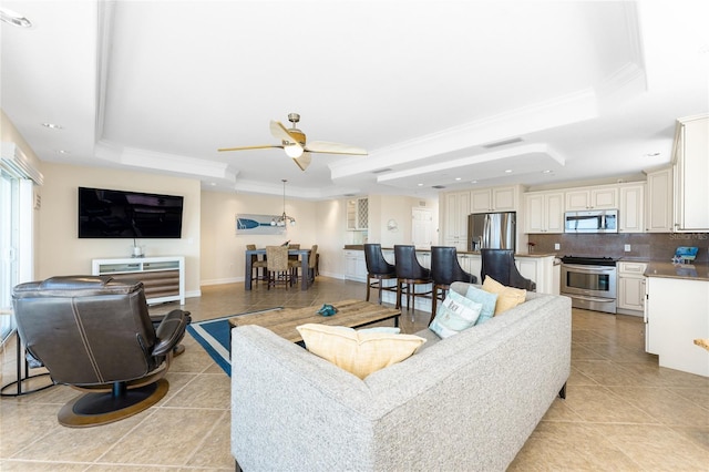 living area with light tile patterned floors, baseboards, ornamental molding, and a raised ceiling