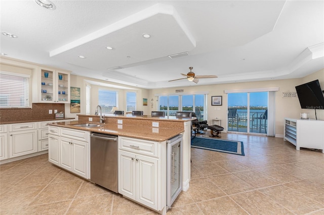 kitchen featuring a sink, plenty of natural light, a tray ceiling, and dishwasher