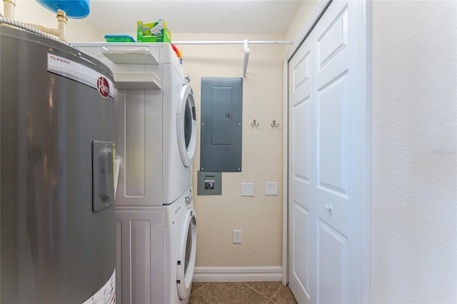 washroom with stacked washer / drying machine, tile patterned flooring, laundry area, electric panel, and baseboards