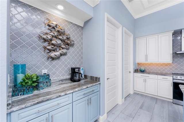 kitchen with wall chimney exhaust hood, light stone counters, ornamental molding, stainless steel electric stove, and backsplash