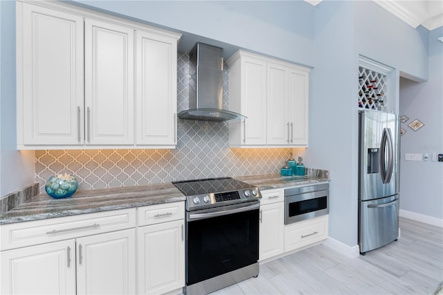 kitchen featuring appliances with stainless steel finishes, white cabinets, backsplash, and wall chimney exhaust hood