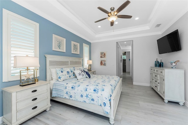 bedroom featuring light wood finished floors, baseboards, a tray ceiling, crown molding, and recessed lighting