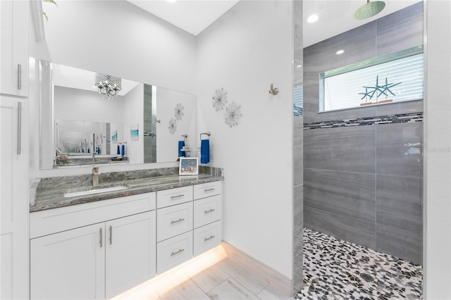 bathroom with wood finished floors, a notable chandelier, vanity, and a walk in shower