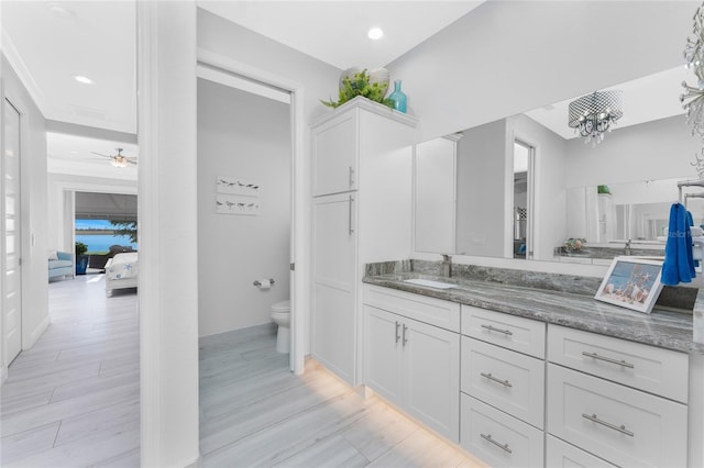 full bath featuring toilet, recessed lighting, ceiling fan with notable chandelier, wood finished floors, and vanity