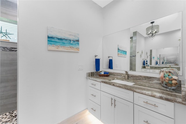 full bath featuring a tile shower, vanity, and an inviting chandelier