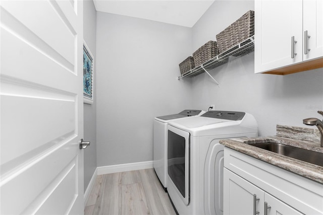 laundry room featuring separate washer and dryer, a sink, light wood-style floors, baseboards, and cabinet space