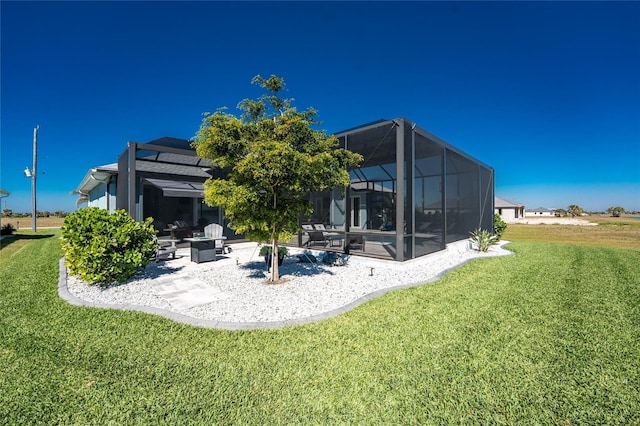 rear view of house with glass enclosure, a lawn, and a patio