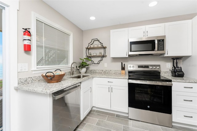 kitchen featuring white cabinets, stainless steel appliances, a sink, and recessed lighting